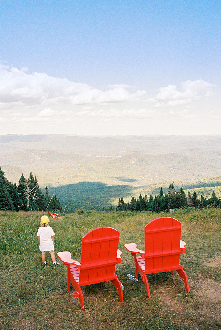 little-boy-enjoying-view-beside-red-chairs-on-mont-tremblant-summit